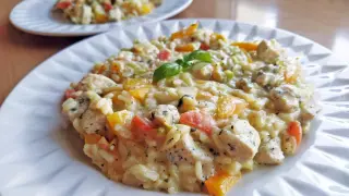 Szybkie risotto z warzywami i kurczakiem, udekorowane listkiem bazylii. Pyszne i kolorowe danie na talerzu.