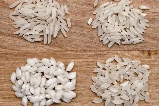 Cztery kupki ryżu na drewnianym tle. Dwie górne to długie ziarna, idealne do risotto. Dwie dolne to krótsze, bardziej okrągłe ziarna.