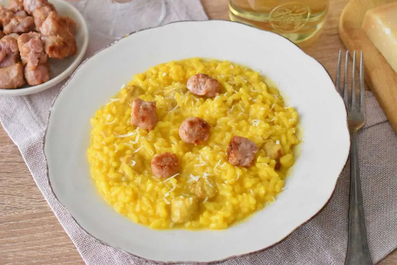 Pyszne risotto alla milanese z kawałkami kiełbasy i parmezanem.