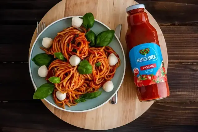 Pyszne spaghetti z passatą Włocławek, ozdobione kulkami mozzarelli i listkami bazylii. Idealny posiłek na każdą okazję.